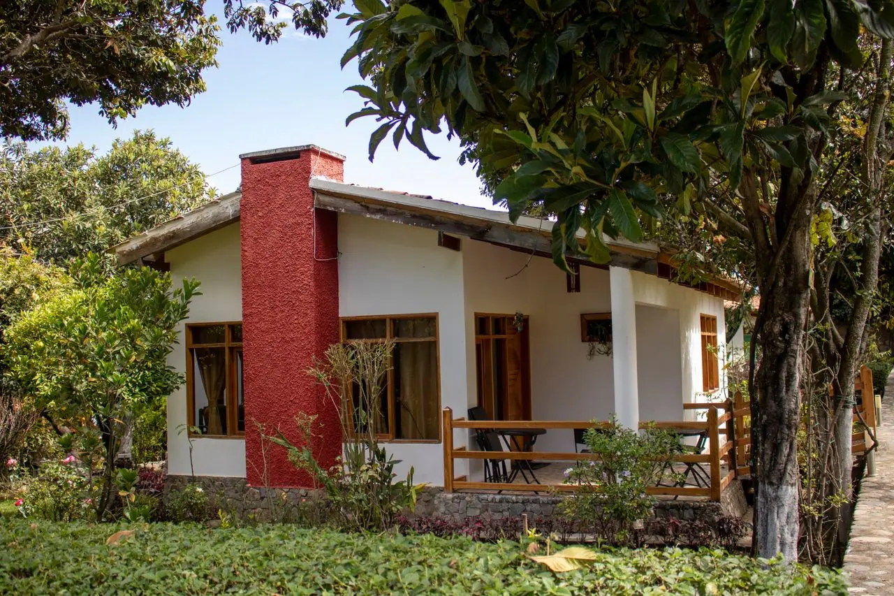 Cabin with a red chimney, wooden porch and fruit trees