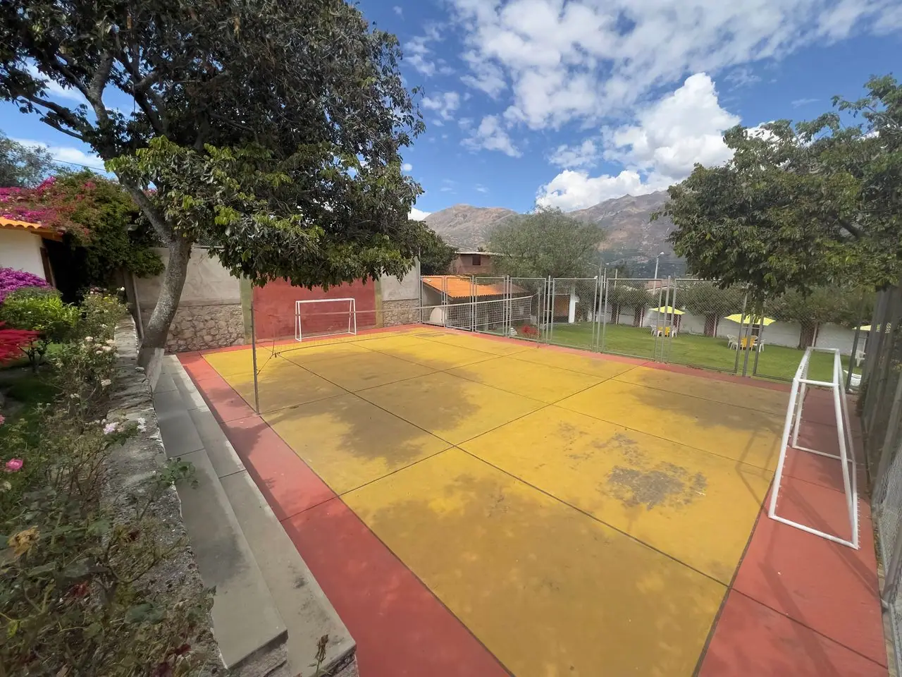 Campo deportivo para fútbol y vóley rodeado de jardines