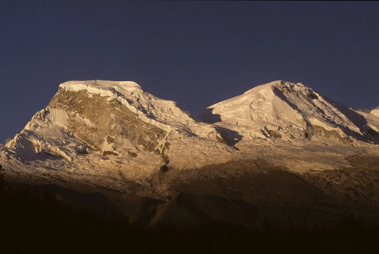 The summits of Huascarán in golden light against a dark sky