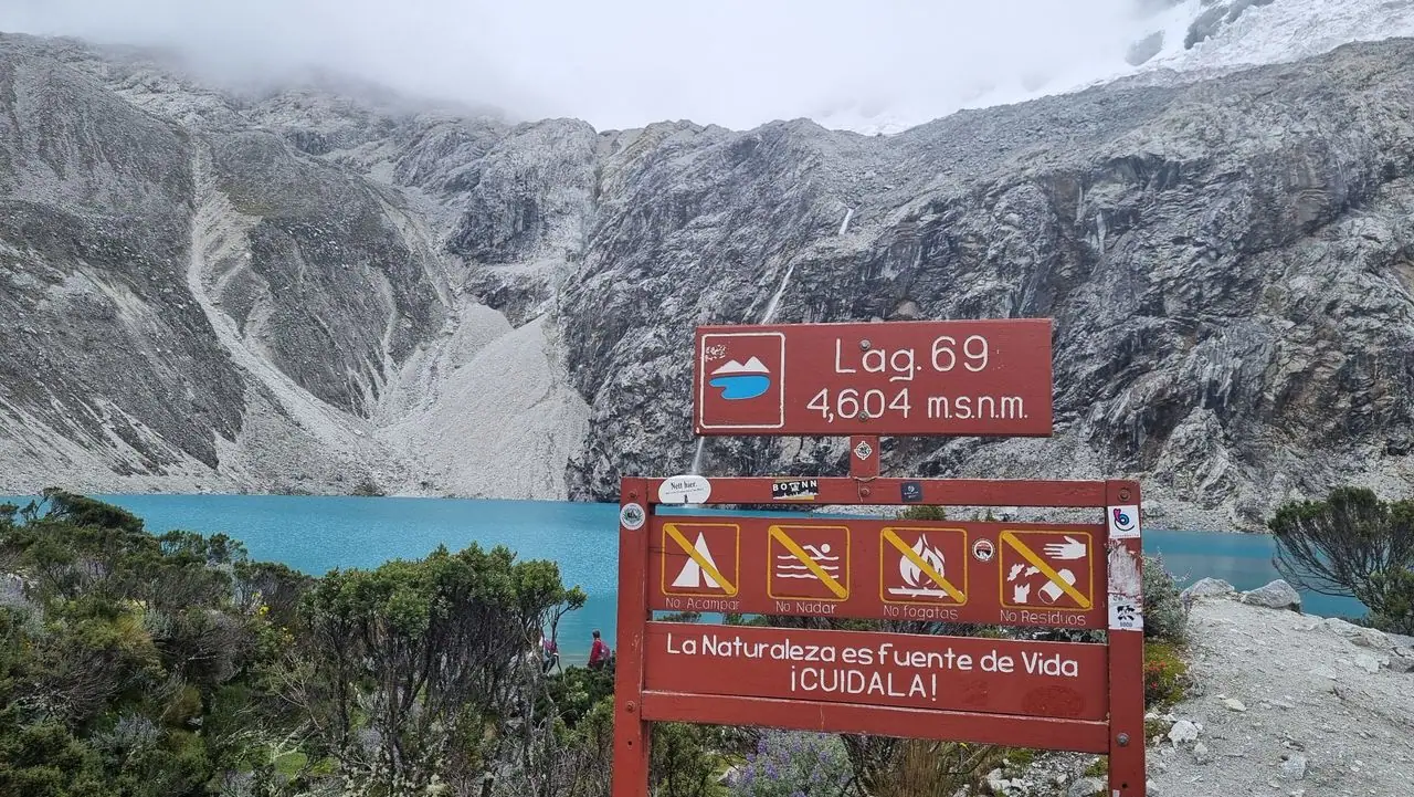 Sign at Laguna 69 showing an altitude of 4,604 m above sea level, with the turquoise lake behind